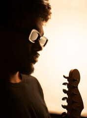 portrait of blind black man musician with glasses and dreadlocks and his guitar studio soft...