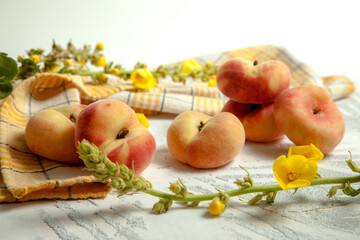 Several whole saturn peaches or flat peach on white wooden background..