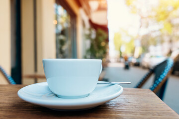white single cup of coffee  and saucer in sidewalk cafe