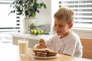 A smiling boy with fresh farm milk and homemade cookies. Breakfast, dairy products