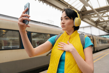 happy female using phone taking selfie at train station   Safety travel concept	