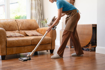 woman with vacuum cleaner cleaning floor  at home