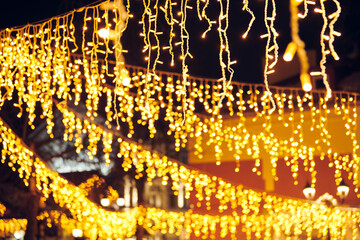 Flickering lights of hanging garlands for New Year christmas street decorations at night, merry...