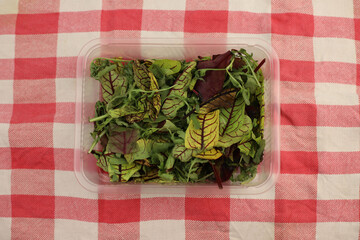 spoiled, limp salad in a plastic transparent container