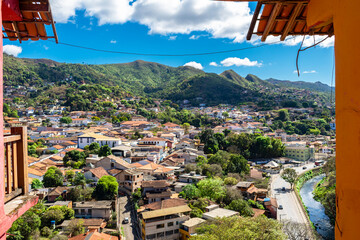 Partial view of the city of Sabará, Brazil. Streets, bridge, mountain, trees and blue sky with clouds.
