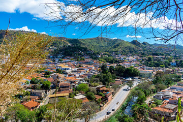 Partial view of the city of Sabará, Brazil. Streets, bridge, mountain, trees and blue sky with clouds.