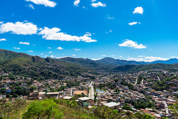 Partial view of the city of Sabará, Brazil. Streets, bridge, mountain, trees and blue sky with clouds.