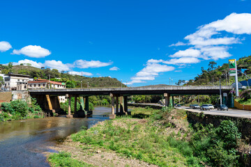 Partial view of the city of Sabará, Brazil. Streets, bridge, mountain, trees and blue sky with clouds.