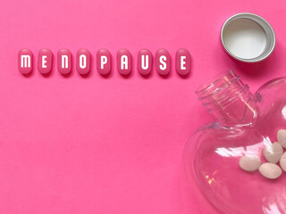 Menopause text on pills with pink colour background. Women health concept.
