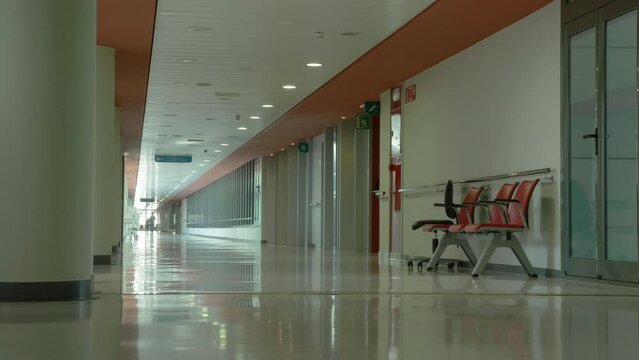Modern hospital lonely corridor with waiting room seating and glass doors