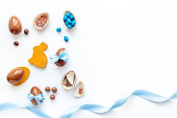 Easter festive background. Chocolate Easter eggs in blue ribbon with sweets