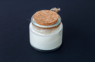 aromatic candle with a wooden wick in a glass candlestick, close-up on a dark background