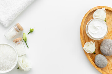 Frame of white cosmetics products and roses flowers, top view