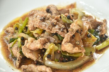 spicy stir fried slice pork meat with onion and sweet chili couple black pepper on plate 
