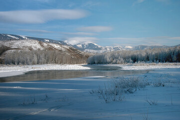 Snowcovered mountain landscape with a frozen river and cloudy sky.