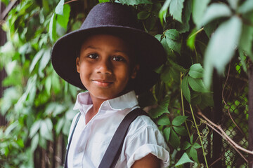 close-up portrait of a boy of African descent near an iron fence covered with ivy