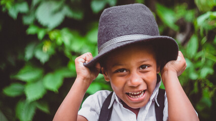 the boy puts the hat on his head while laughing