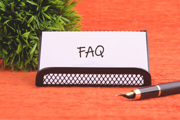 FAQ (Frequently Asked Questions) symbol on a white business card supplied with a fountain pen and...