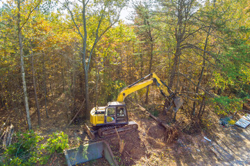 Preparation of land for construction, use of an excavator tractor to uproot trees make space for...