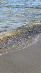 Calm waves gently touching the sandy shore. Clear water reflecting the sunlight, creating a serene and peaceful beach scene