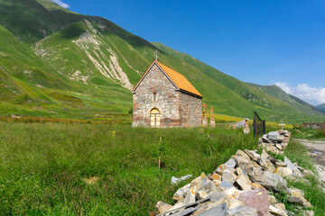 Small church with tiled roof of Abano nunnery. Green grass and mountains around