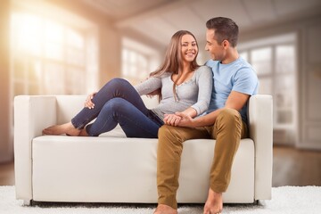 Joyful young couple sitting on a sofa at home