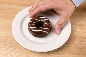 The chocolate donut is taken from the plate. Passion for sweets.