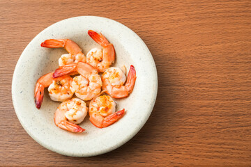 Close up photo of Grilled shrimp without skin served on a small plate and placed on the wooden table. Concept for whole natural protein and omega-3. Empty blank copy text space.