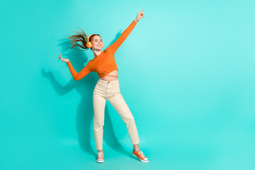 Full length photo of lovely woman wear crop top dancing in headphones look directing empty space isolated on turquoise color background