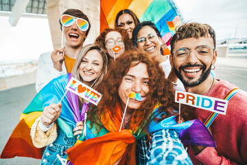 Diverse group of cheerful young people celebrating gay pride day - Lgbt community concept with guys and girls hugging together outdoors