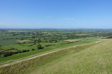 Scenic landscape view of green farmland fields and clear blue sky above seen from a high vantage...