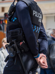 Formation of Spanish police squads with the emblem of the "Local Police" in uniform maintains public order on the streets of Spain Rear view of a police officer with the Spanish text "Policia Local"