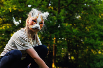 Cute young little kid girl wear cat furry mask enjoy have fun playing outdoors in forest street...