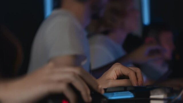 Focus on hand with gaming keyboard, close up gamers play video game on PC at computer club, cyber sport tournament. E-sport championship. Multiplayer online real-time strategy RTS first-person shooter