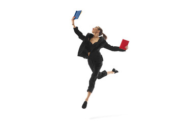 Fototapeta premium Businesswoman in mid-air pose, reading book in a jump, showcasing corporate success and continuous learning, isolated on white background. Concept of business, office lifestyle, professional growth