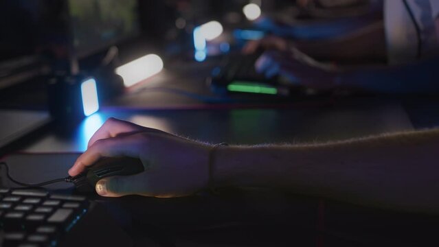 Gamers play video game on PC at computer club. Finger clicks on button of mouse with RGB lightning. Professional E-sport tournament Cyber sport team. Multiplayer tactical first-person shooter strategy