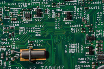 Green circuit board with various electronic components.