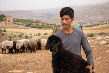 young arabian male holding black sheep in his hand with cheerful look on his face feeling happy in eid al adha