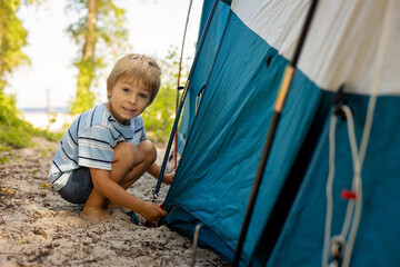 Happy family, kids, boy brothers and a dog,playing around pitched tent on the beach, while wild...