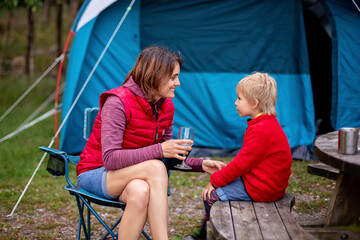 Mother and child, sitting in front of a tent, drinking and having family time together