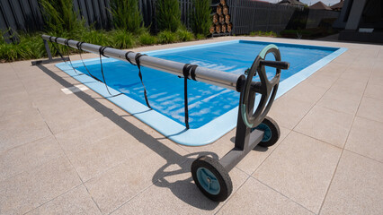 Home outdoor pool covered with film to save chemicals, water and heat preservation