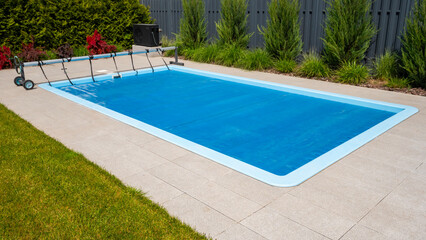 Home outdoor pool covered with film to save chemicals, water and heat preservation