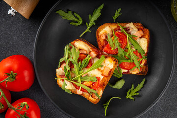 Tasty crunchy toasts pizza. Fast food, modern variation of portioned quick made pizza on toast bread with tomato, bacon, mozzarella cheese and arugula, copy space