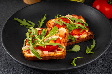 Tasty crunchy toasts pizza. Fast food, modern variation of portioned quick made pizza on toast bread with tomato, bacon, mozzarella cheese and arugula, copy space