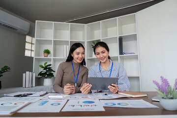 Two Asian women collaborating on a project in a modern office. Concept of teamwork, business, and productivity