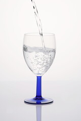 Eingiessen von Wasser in Wassserglas mit Perlen