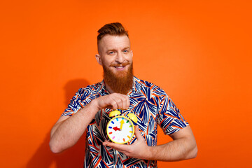 Photo of positive good mood guy dressed print shirt showing clock isolated orange color background