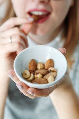 Woman Eating Nuts, a healthy snack full of minerals. Closeup Of Female Mouth Biting Nut. 