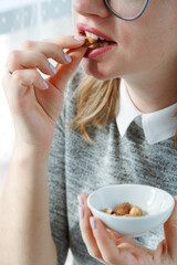 Woman Eating Nuts, a healthy snack full of minerals. Closeup Of Female Mouth Biting Nut. 