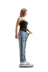 Woman wearing a big size jeans and weighing on a medical scale